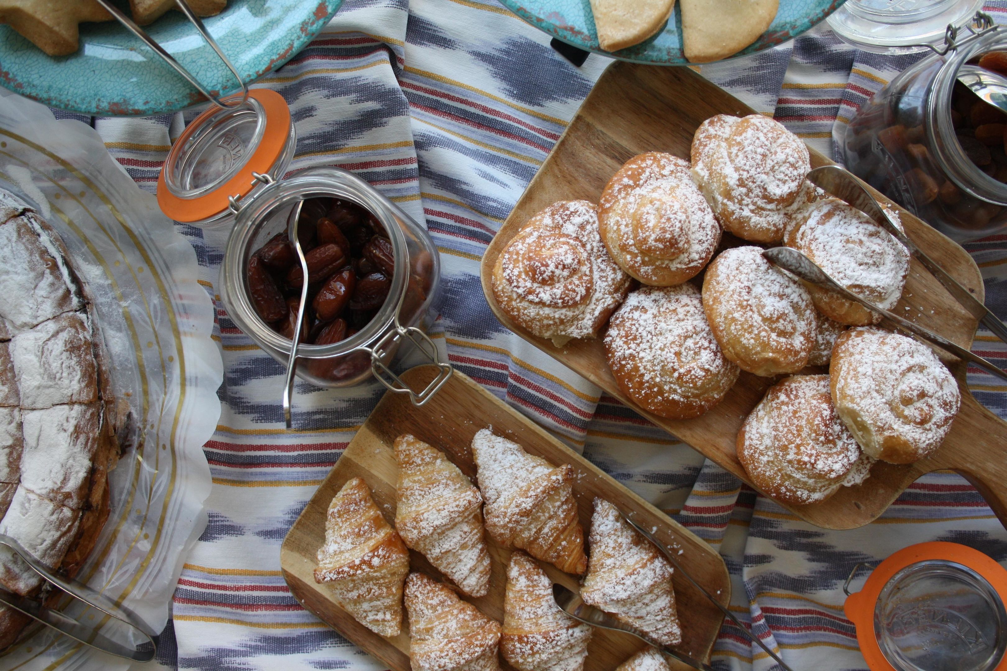 A table with pastries, a jar of dates, and a loaf of bread.