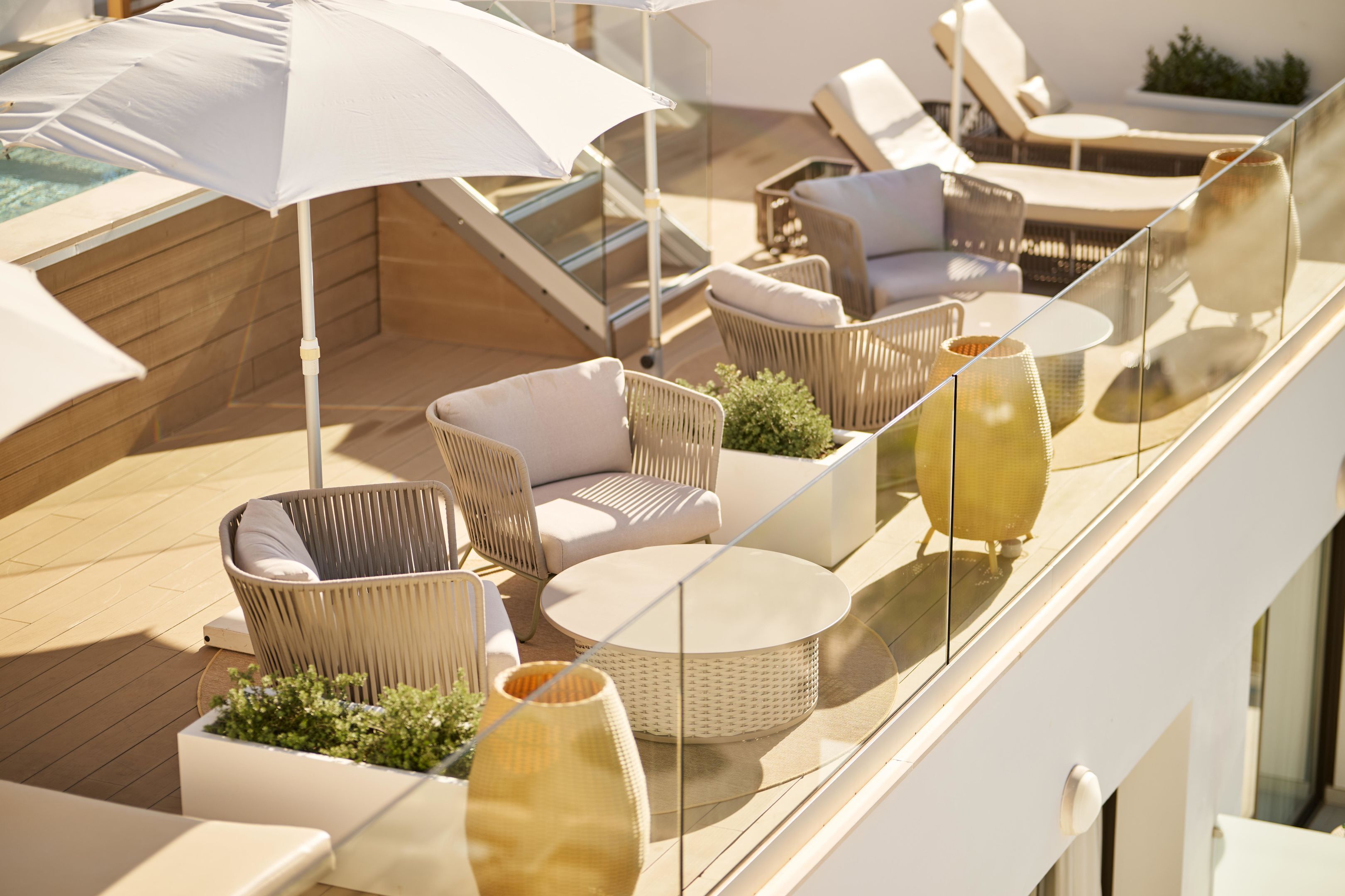 A balcony with wicker furniture, a round table, and a large umbrella.
