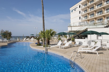 Una piscina al aire libre, sombrillas, sillones reclinables de piscina