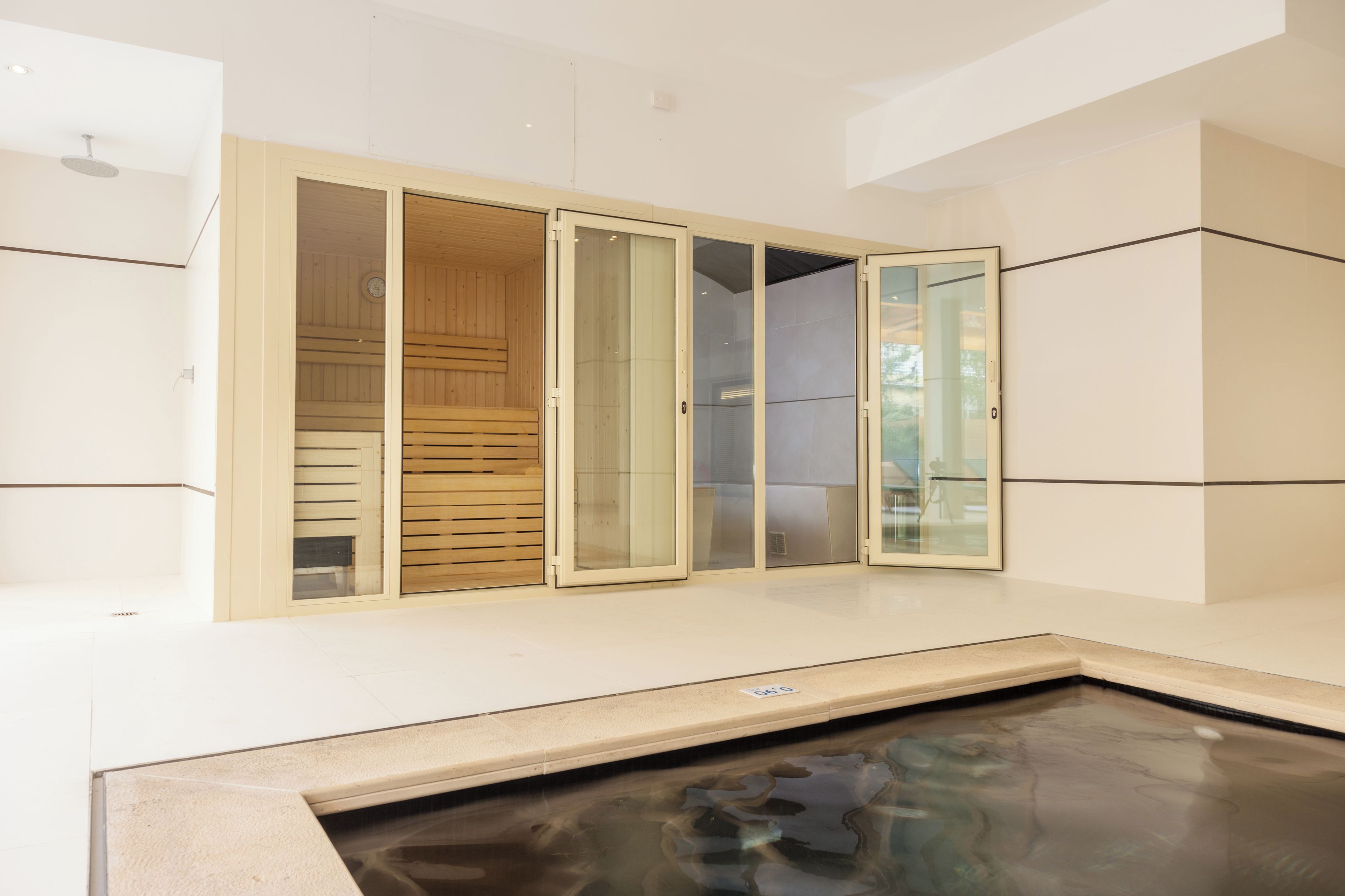 Un espace détente avec un jacuzzi, des bancs en bois et des portes en verre.