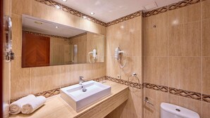 Un baño moderno con un espejo grande, un lavamanos y una ducha.