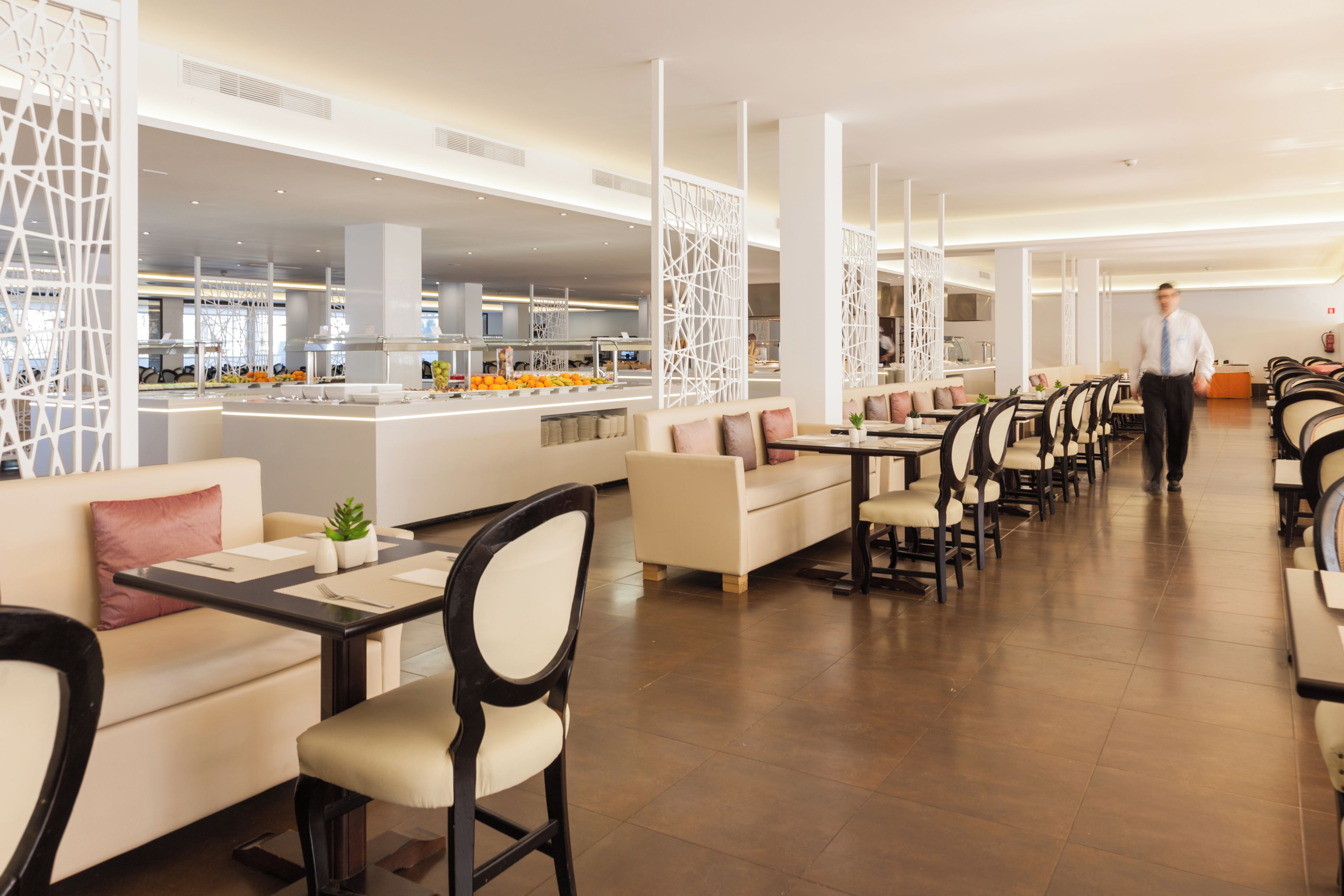 Un restaurant moderne avec un long comptoir, des sièges confortables et une cuisine située au fond de la salle.