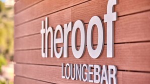 Letrero que dice 'theroof loungebar' con fondo de madera.