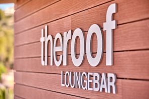 Letrero que dice 'theroof loungebar' con fondo de madera.