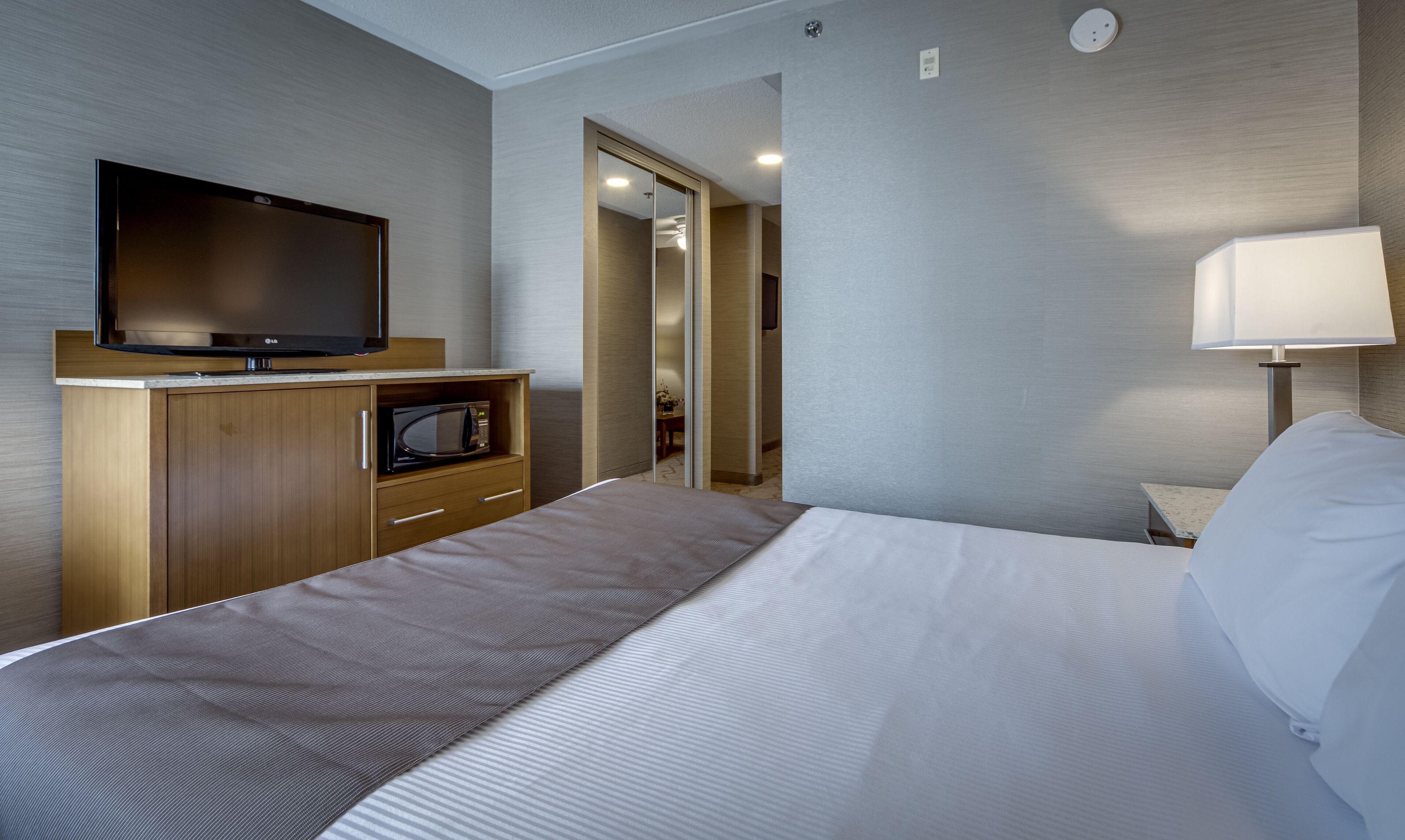 Ein Hotelzimmer mit Bett, Fernseher, Mikrowelle, Lampe und Spiegel.