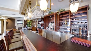 Un espace bar avec des chaises en bois, un long comptoir et des étagères remplies de bouteilles et de verres.
