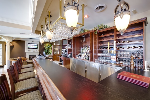 A bar area with wooden chairs, a long bar counter, and shelves stocked with bottles and glasses.