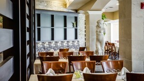 Un restaurant avec des chaises et des tables en bois, un mur en pierre et une statue.