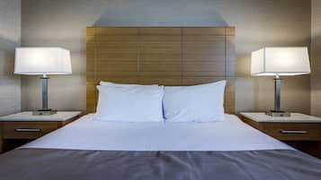 A hotel room with a large bed, two bedside tables, and two lamps.