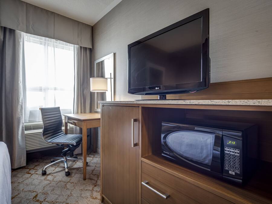 Una habitación de hotel con televisión, microondas, escritorio y silla.