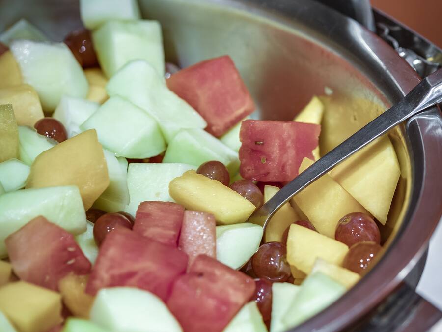 A bowl of fruit salad with a spoon.