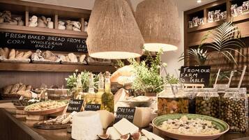 A food display with various breads, cheeses, and olives.