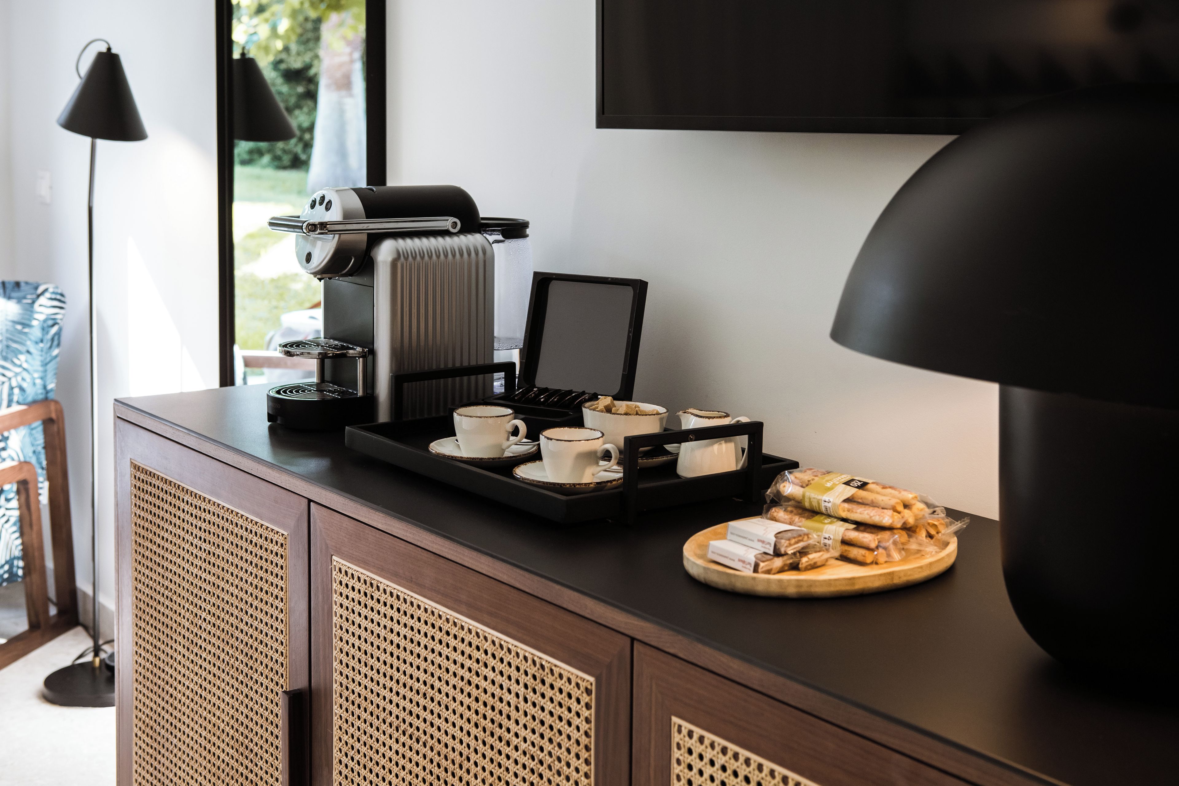 A kitchenette with a coffee machine, tea set, and pastries on a tray.