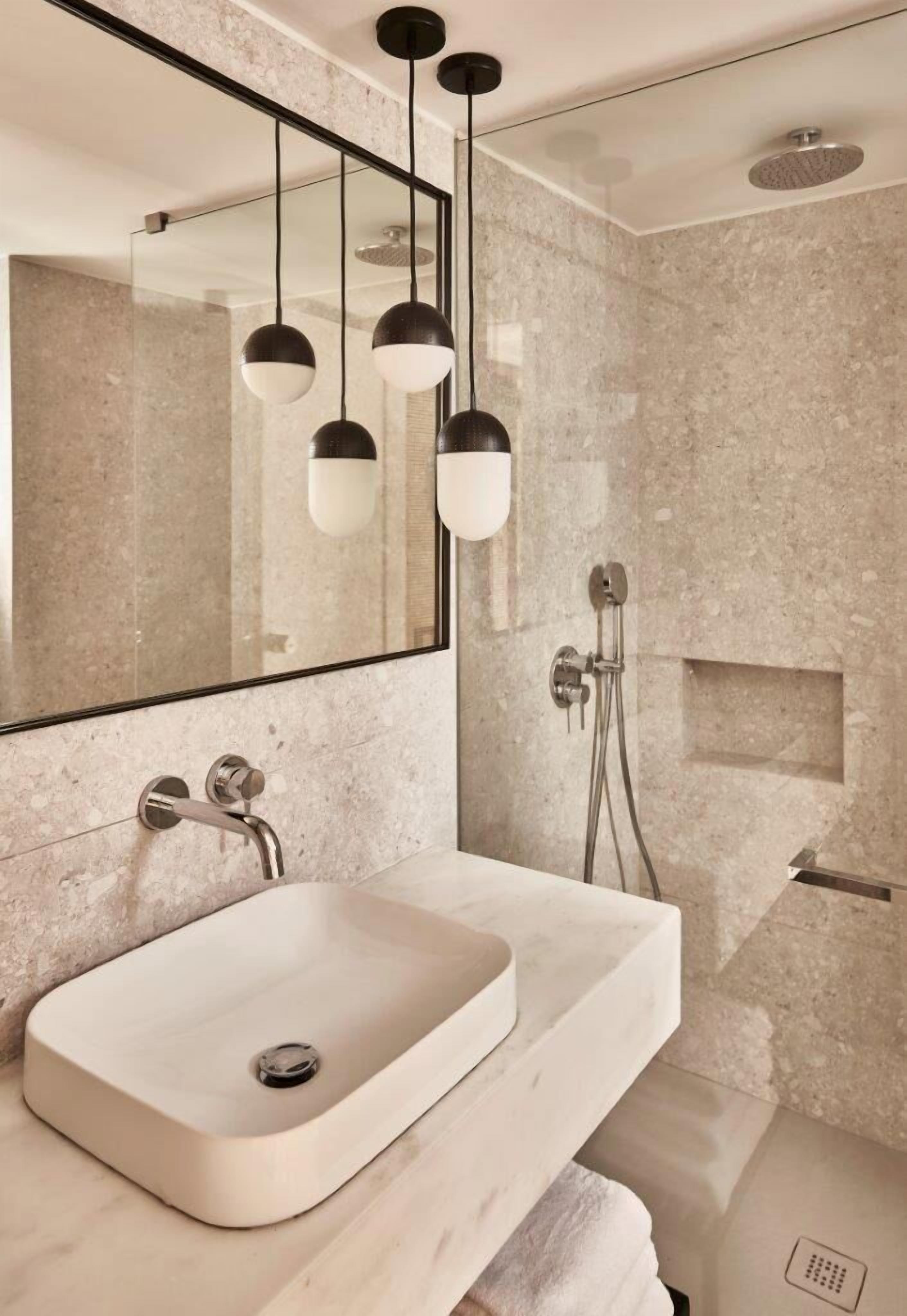 Un baño moderno con un espejo grande, un lavamanos rectangular y una zona de ducha.