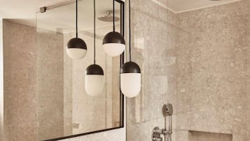Un baño moderno con un espejo grande, un lavamanos rectangular y una zona de ducha.