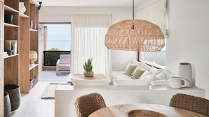Ein modernes Wohnzimmer mit einer Holzbibliothek, einem weißen Sofa, einem Esstisch und einer großen gewebten Pendelleuchte.