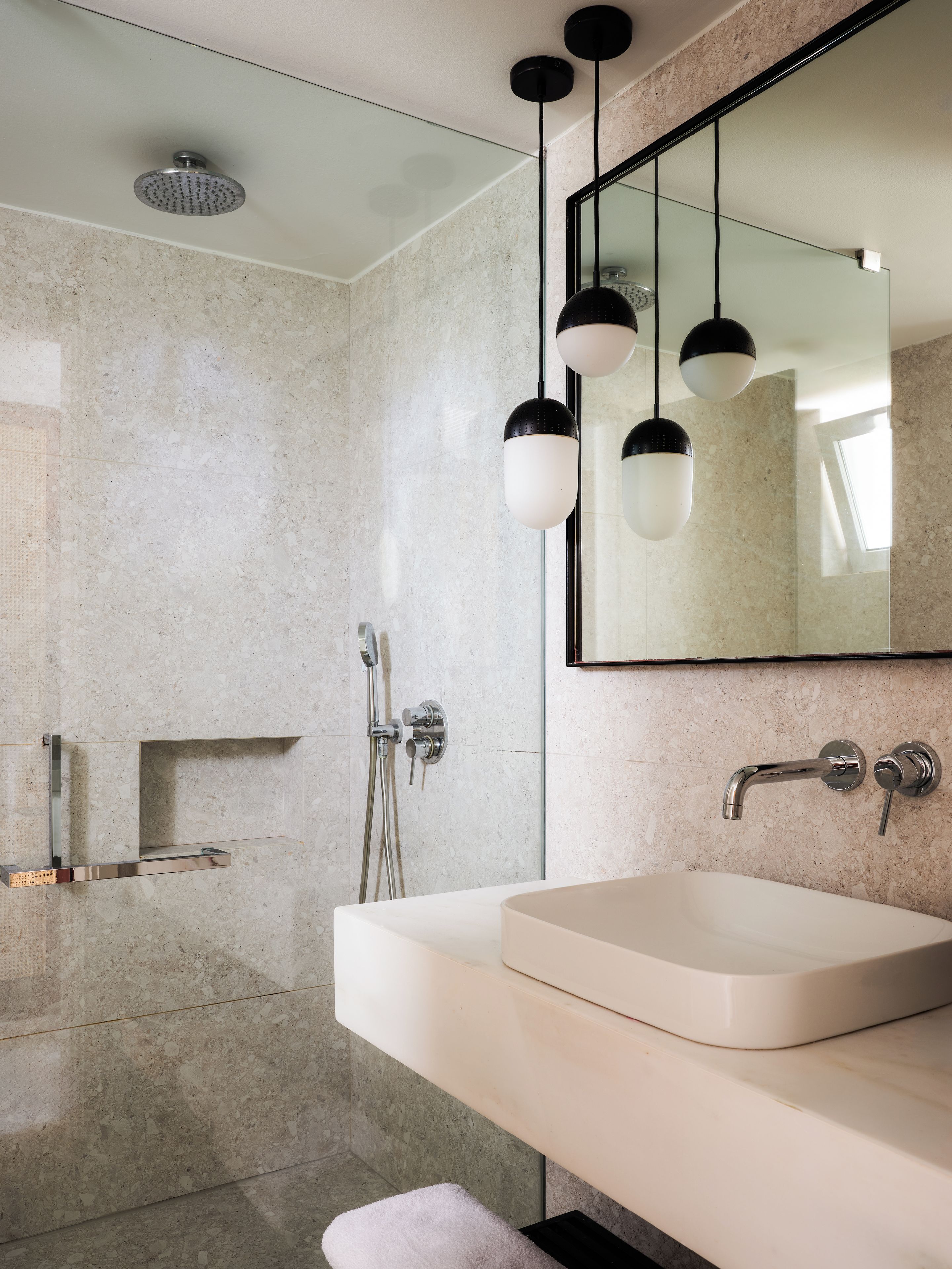 A modern bathroom with a large mirror, a sink, and a shower area.