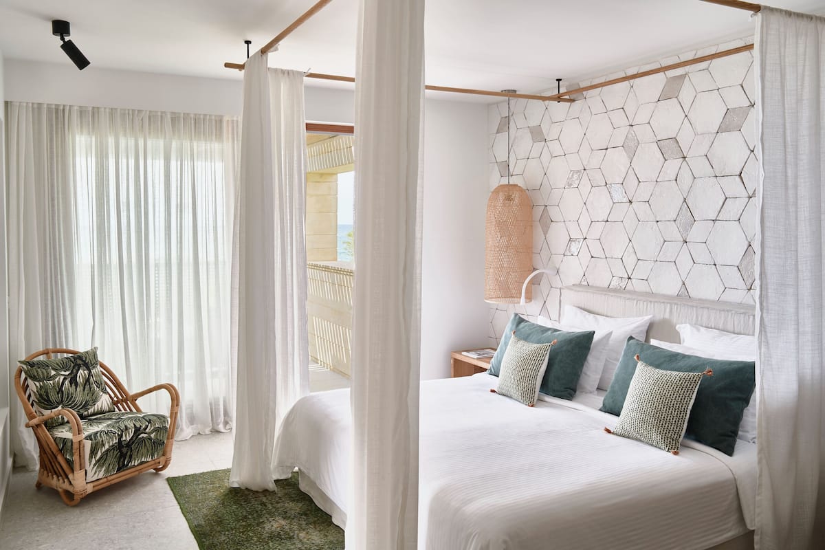Ein Schlafzimmer mit Bett, einem Sessel und Blick ins Freie.