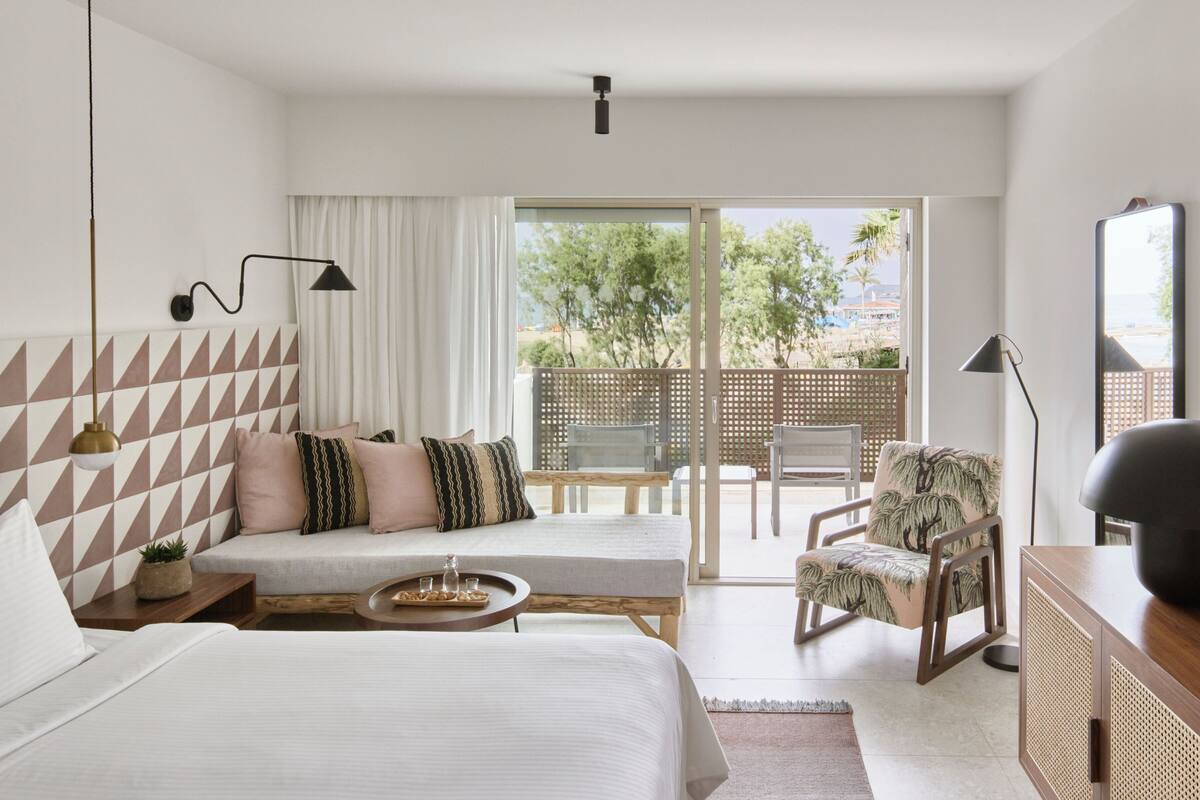 Ein modernes Hotelzimmer mit zwei Betten, einem Balkon und Blick ins Freie.