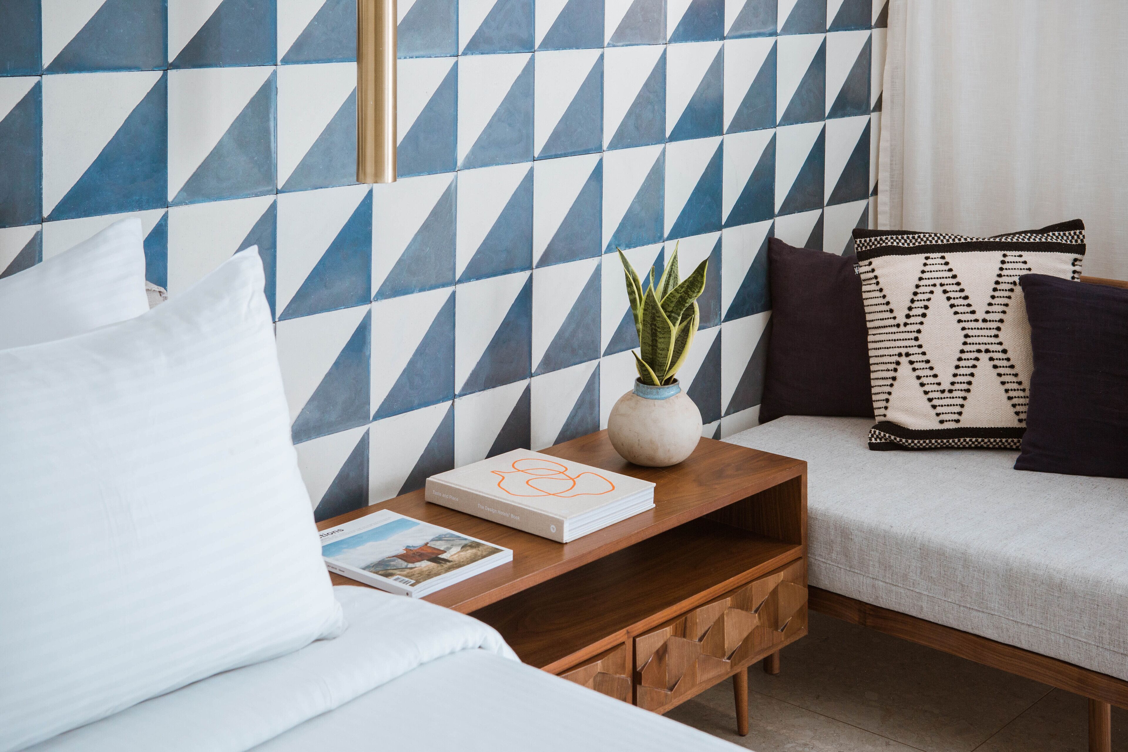 A neatly arranged bedroom with a bed, bedside table, and a sofa.