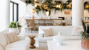 Un salon moderne avec un canapé blanc, une table basse et un coin repas comprenant des chaises et une table.