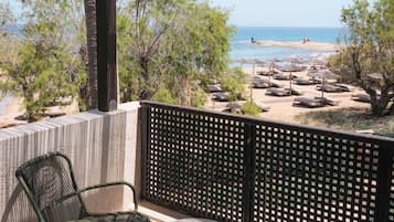 Un balcón con vistas a la playa, una mesa y sillas.