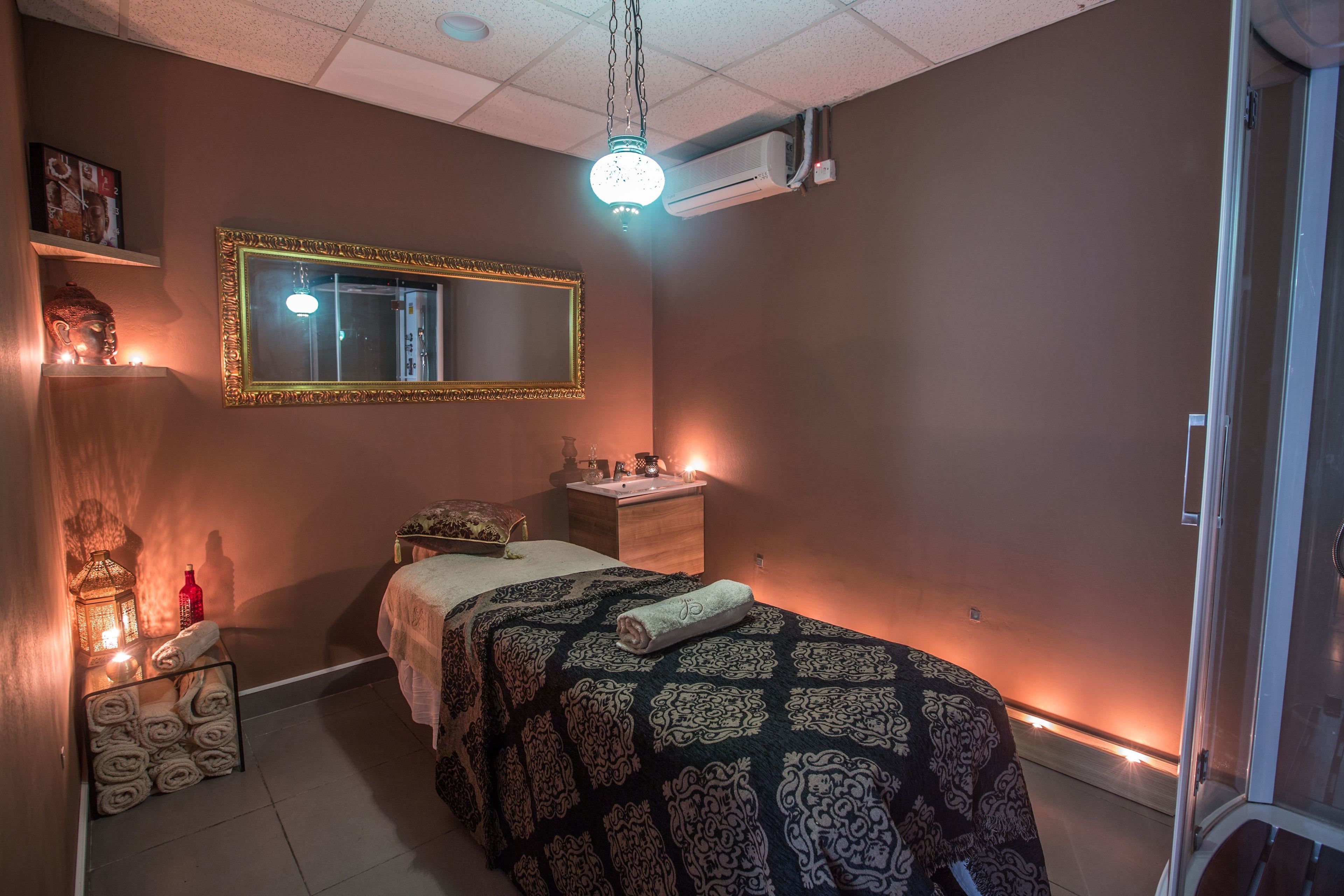Habitación de hotel con cama, tocador con espejo, lavabo y aire acondicionado instalado en la pared.