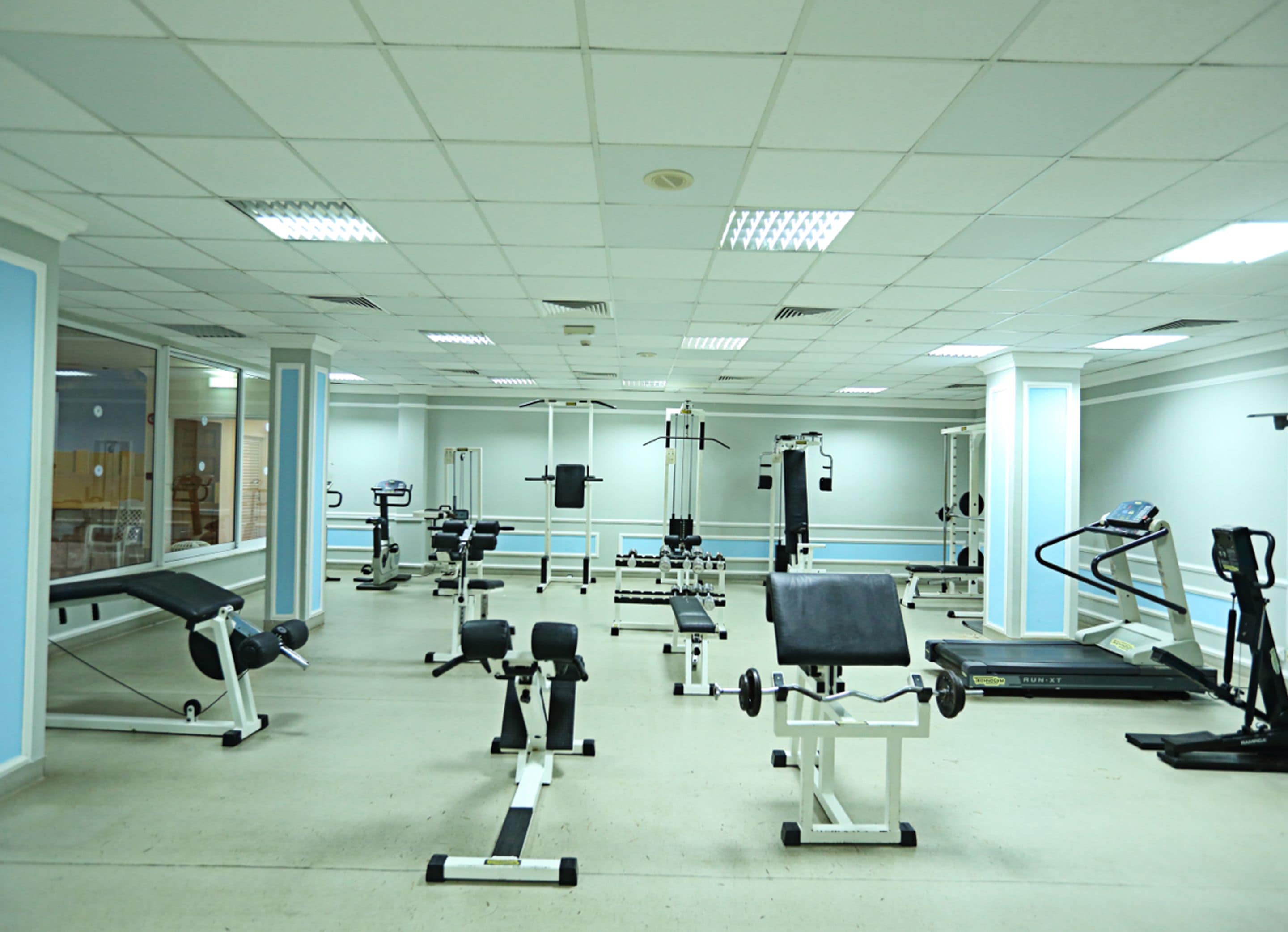 A gym with various exercise equipment, including treadmills, weight machines, and free weights.