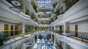 Ein mehrgeschossiges Atrium mit Sitzbereichen, Grünpflanzen und einem zentralen, offenen Bereich.