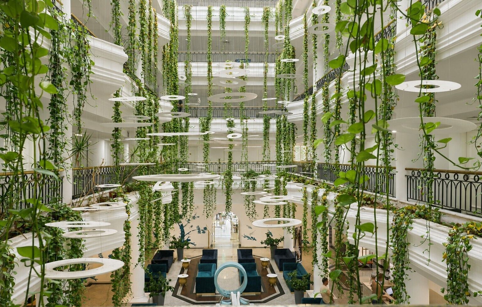 A multi-level atrium with hanging plants, circular platforms, and seating areas.