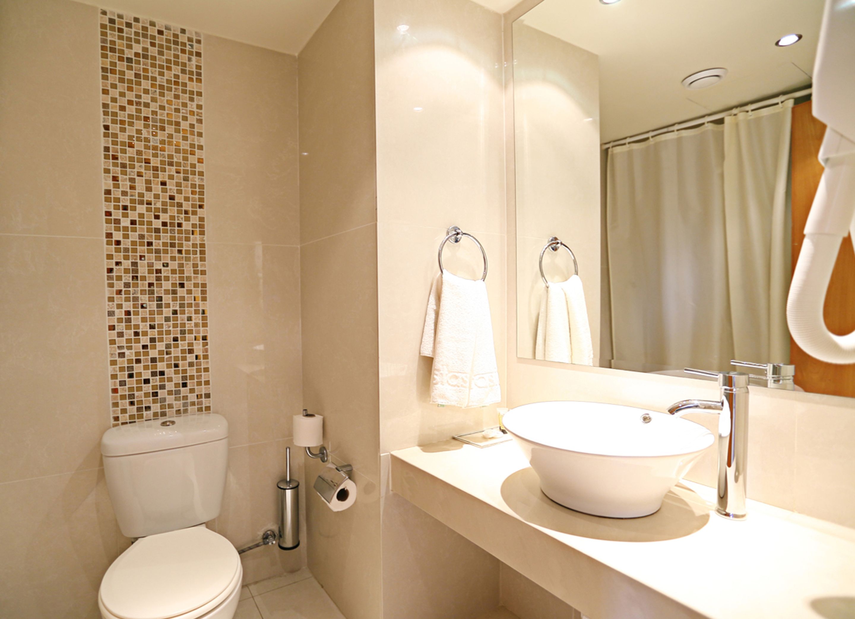 A modern bathroom with a toilet, bidet, sink, and a large mirror.