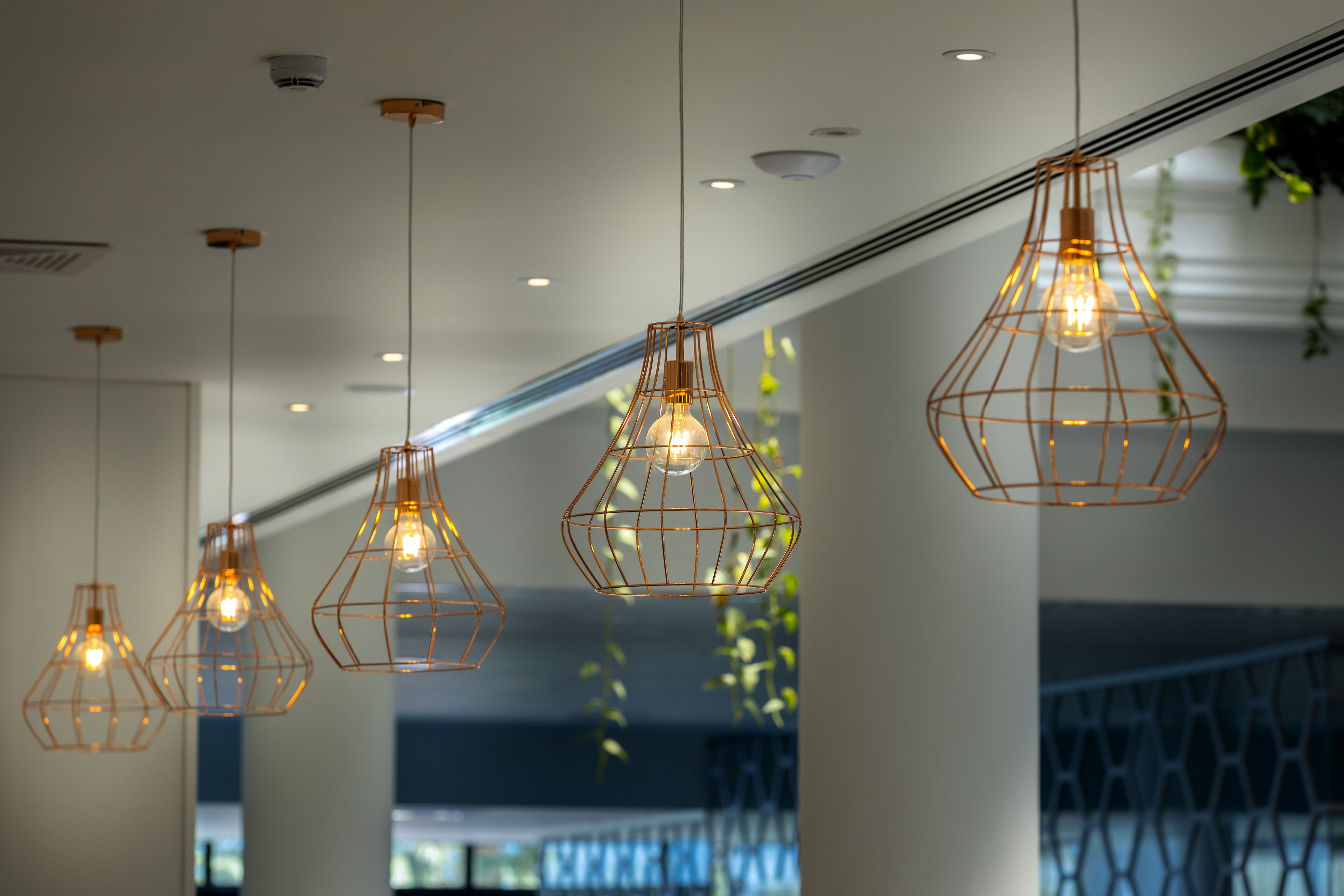 Un intérieur moderne agrémenté de plusieurs luminaires suspendus et d’une bouche d’aération visible au plafond.