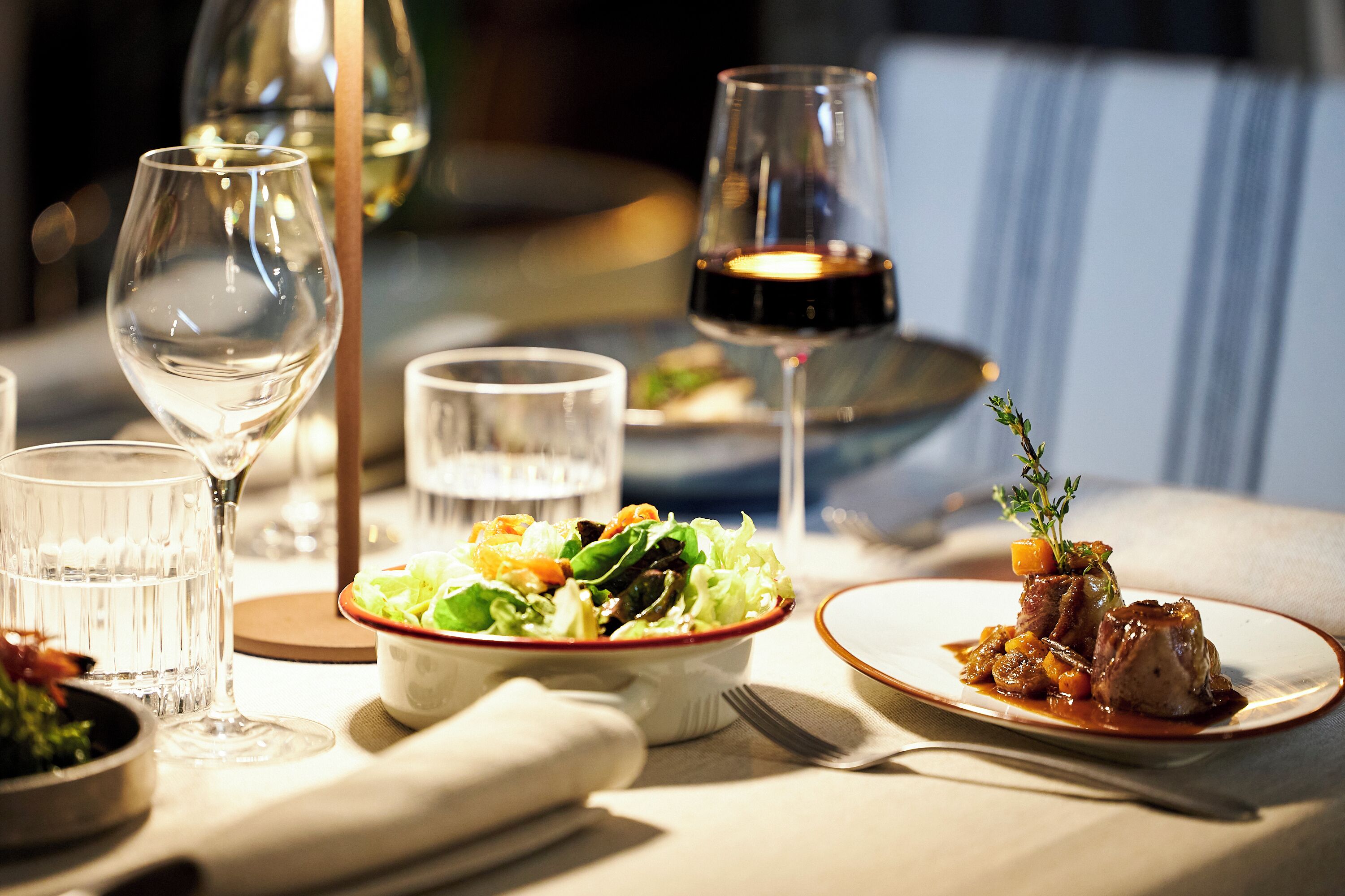 A dining table with a plate of food, a glass of wine, and a glass of water.