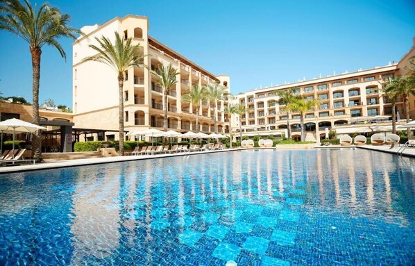 Relax by the pool surrounded by lounge chairs and umbrellas, with a beautiful view of the hotel's classical architecture.