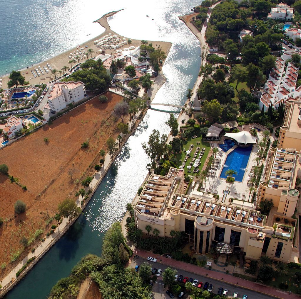 Vista aérea de un complejo turístico en la costa con piscina, playa y río.