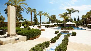 A resort pool area with palm trees, lounge chairs, and a large pool.