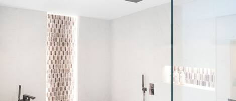 A modern bathroom with a freestanding bathtub, a glass shower enclosure, and a tiled shower area.