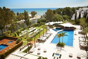A resort with a large swimming pool, sun loungers, and a view of the sea. - Insotel Fenicia Prestige Suites & Spa (Santa Eulalia del Rio)