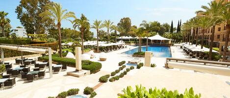 A resort pool area with lounge chairs, umbrellas, and a clear blue pool.