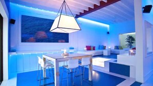 Una cocina moderna con comedor, que cuenta con una isla grande, taburetes de bar y una lámpara colgante.