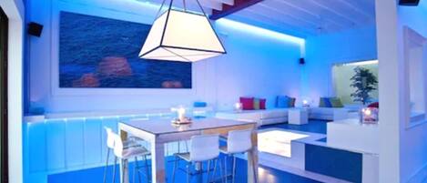 A modern kitchen with a dining area, featuring a large island, bar stools, and a pendant light.