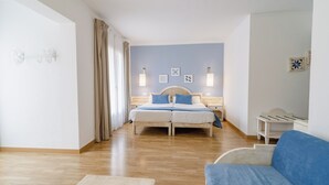 Un dormitorio con una cama doble, mesitas de noche, un sofá azul y suelo de madera.