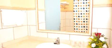 A bathroom with a white sink, a mirror, and a trash bin.
