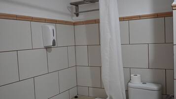 A bathroom with a bathtub, toilet, and a hand soap dispenser.