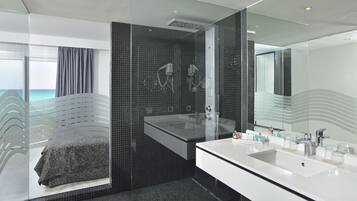 A modern bathroom with a large mirror, a white sink, and a shower area.