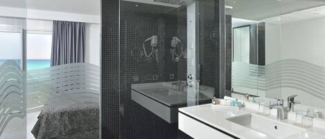 Un baño moderno con un espejo grande, un lavabo blanco y una zona de ducha.