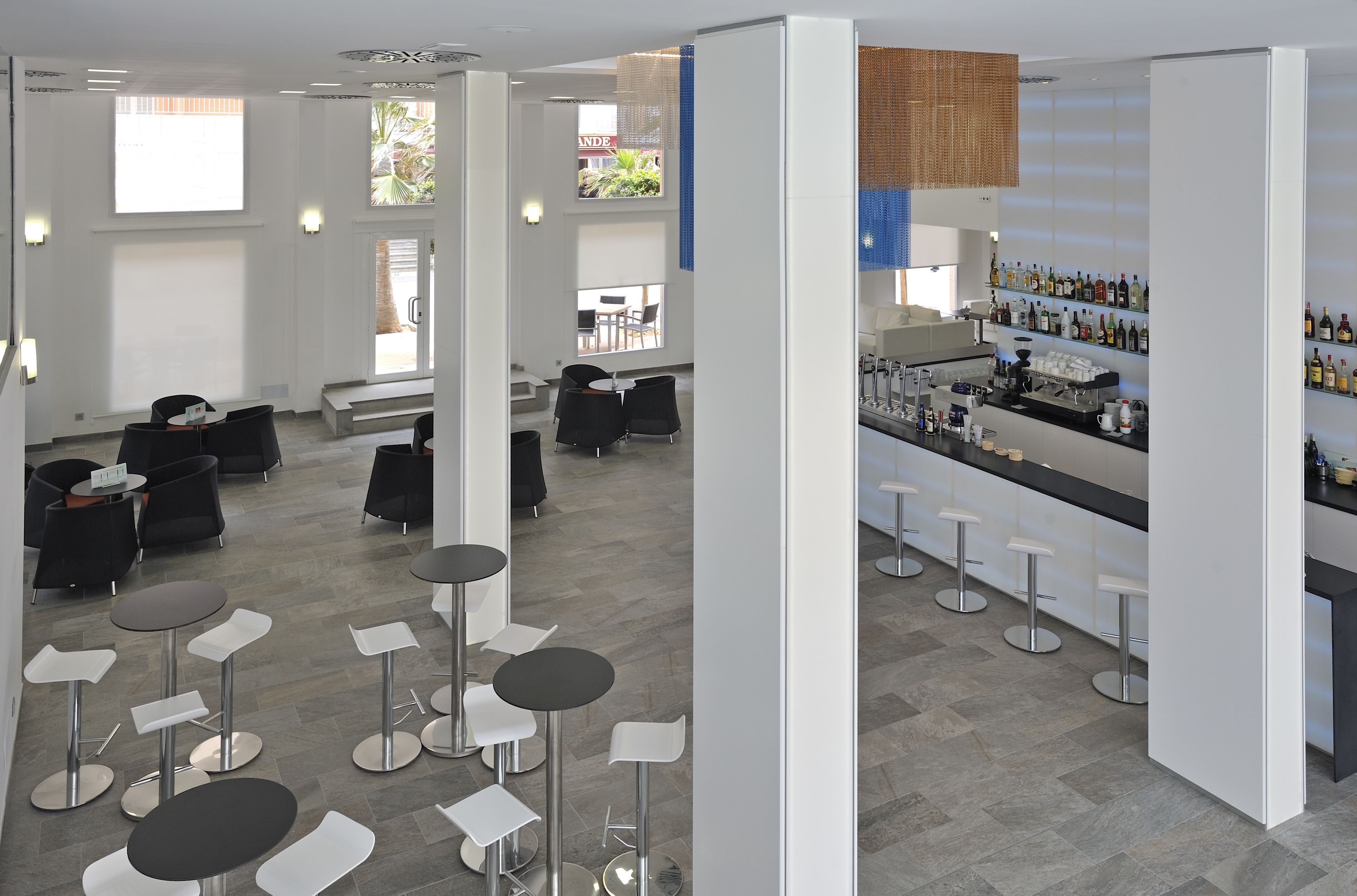 A modern bar area with multiple stools and a bar counter stocked with bottles.