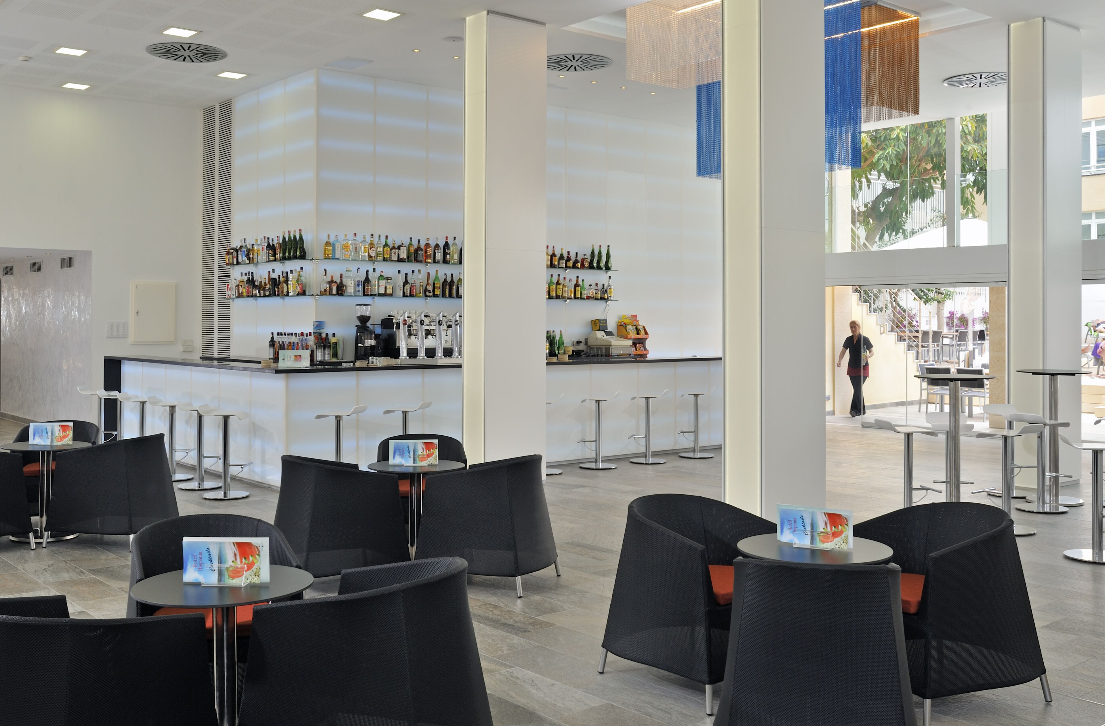 Un área de bar moderna con diversas opciones de asientos y una barra bien surtida.
