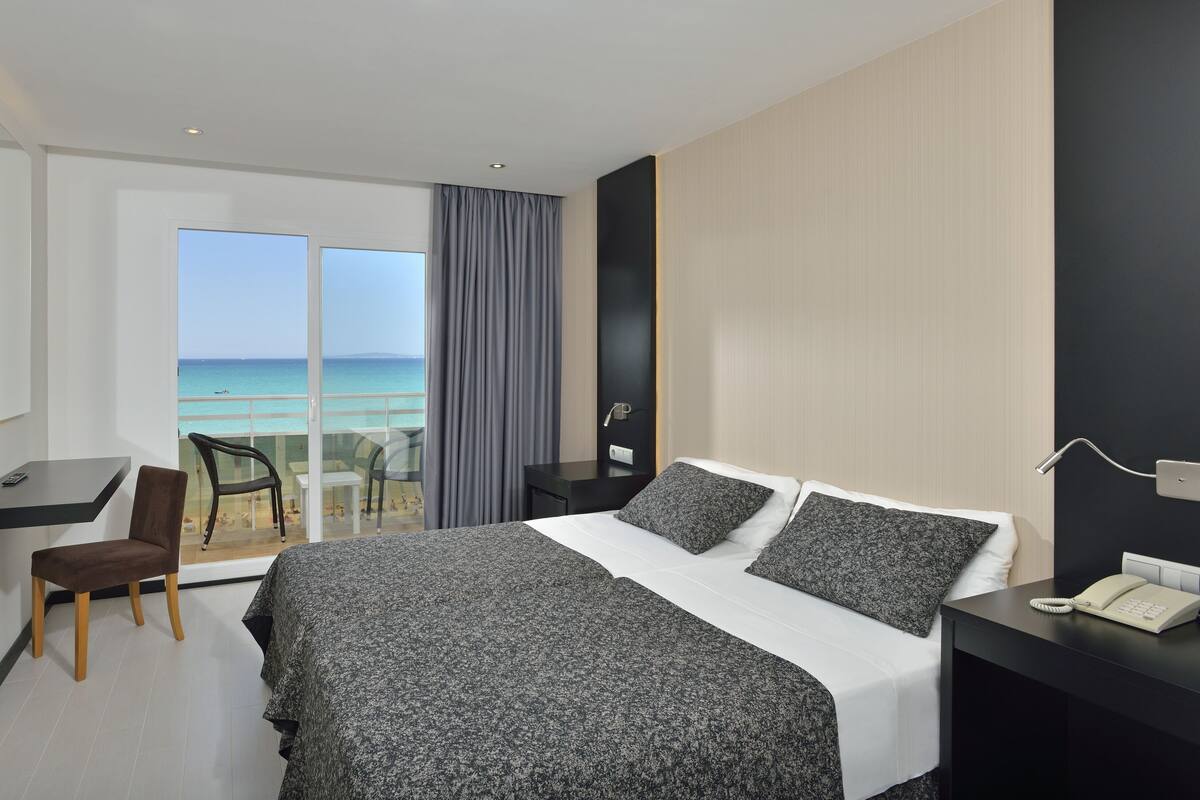 Ein Hotelzimmer mit Bett, Nachttisch, Sessel und Meerblick.