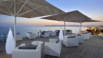 Relax in style with a view of the sea and cityscape from this outdoor seating area, featuring comfortable sofas and armchairs.